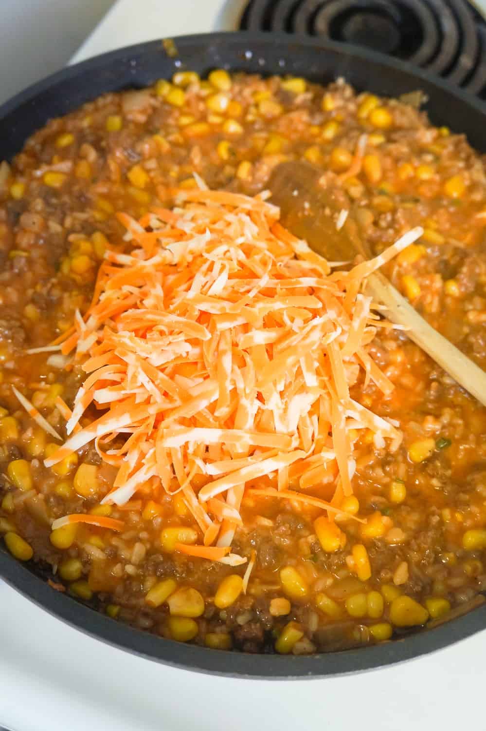 shredded cheddar cheese on top of cheesy tomato ground beef and rice