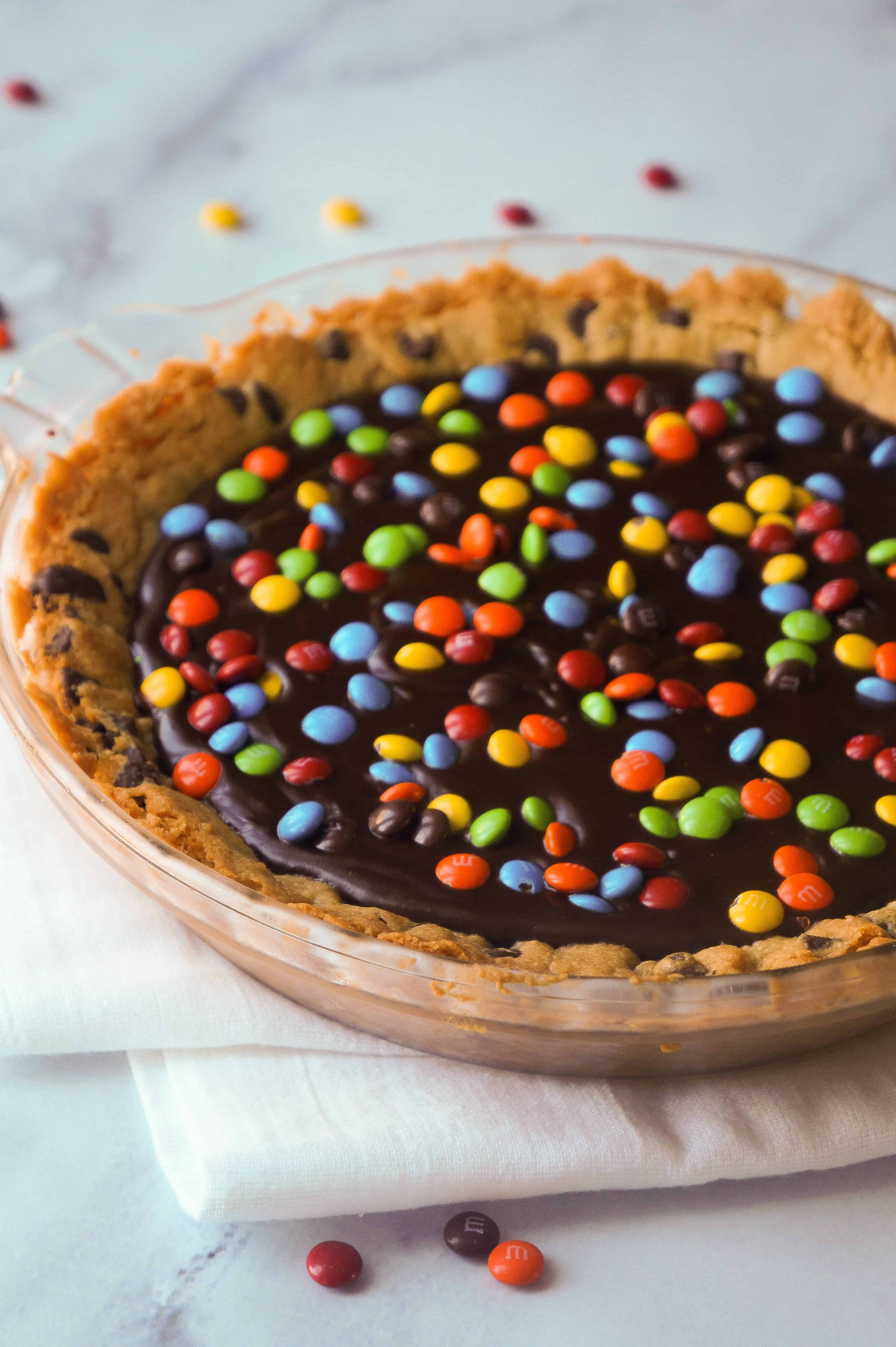 Chocolate Fudge Cookie Pie is a decadent dessert for chocolate lovers. This easy pie recipe starts with a chocolate chip cookie crust with a creamy chocolate filling and is topped with mini M&Ms.