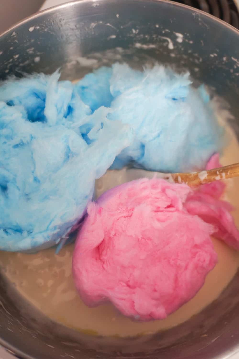 pink and blue cotton candy added to melted marshmallow mixture in saucepan