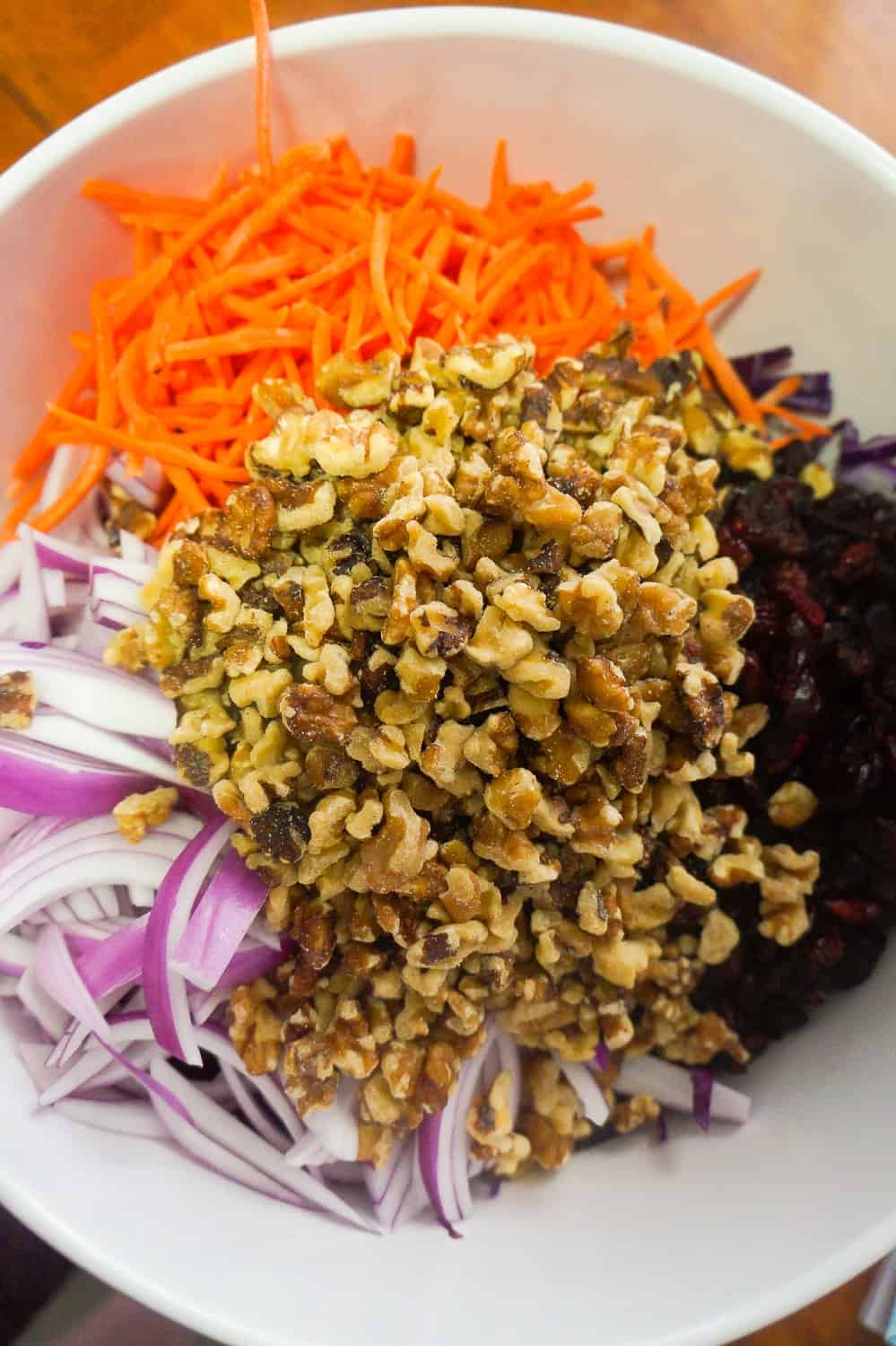 shredded carrots, sliced onion, walnut pieces and dried cranberries in a mixing bowl