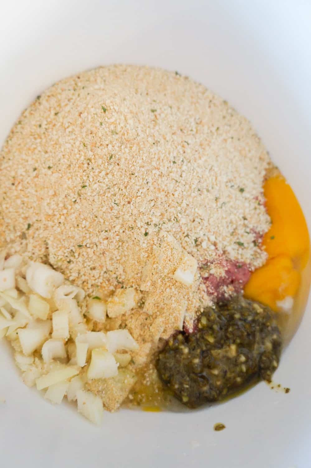 bread crumbs, diced onions, egg and pesto in mixing bowl