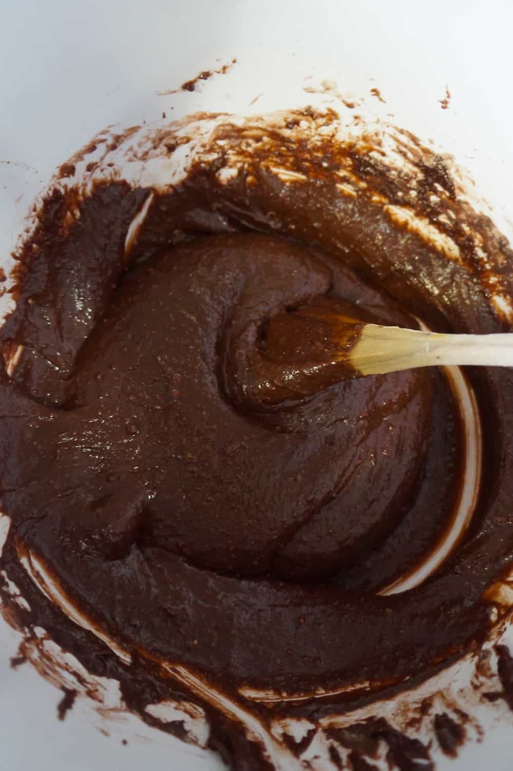 brownie batter in a mixing bowl with a wooden spoon
