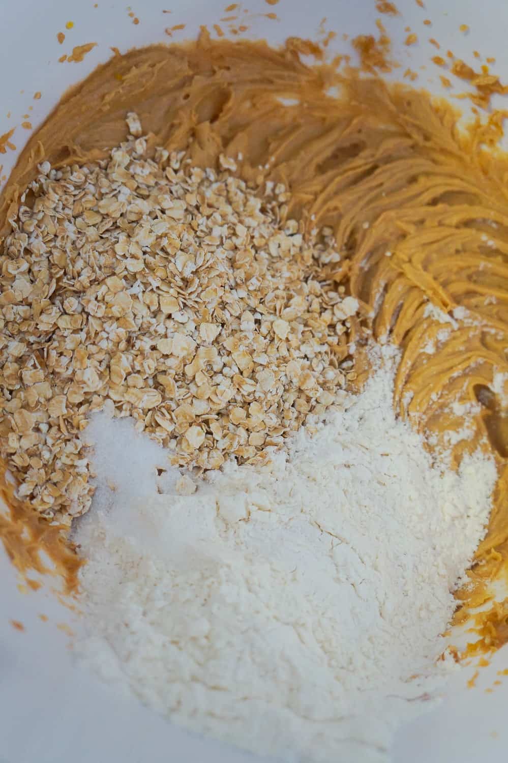 flour and oats added to peanut butter mixture in mixing bowl