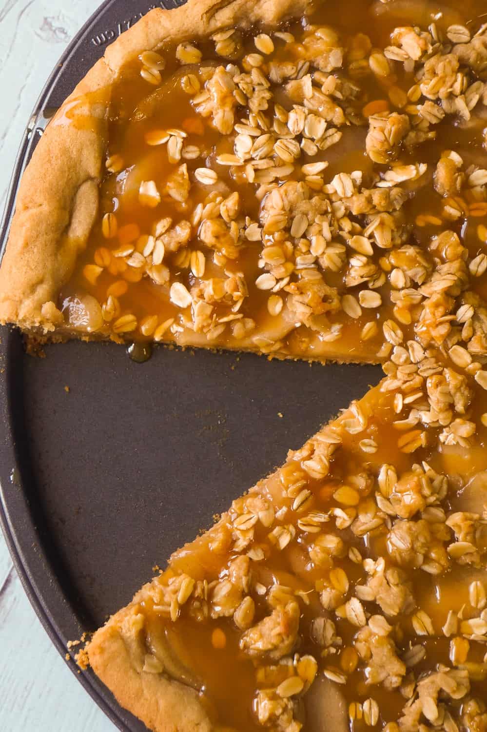 Peanut Butter Apple Pie Cookie Pizza is an easy dessert recipe for peanut butter lovers. A peanut butter cookie crust is topped with apple pie filling, peanut butter oat crumble and drizzled with caramel syrup.