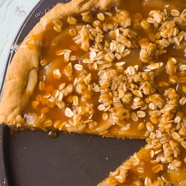 Peanut Butter Apple Pie Cookie Pizza is an easy dessert recipe for peanut butter lovers. A peanut butter cookie crust is topped with apple pie filling, peanut butter oat crumble and drizzled with caramel syrup.