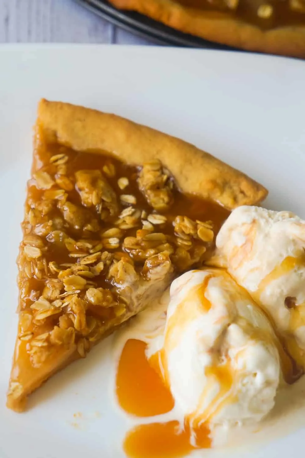 Peanut Butter Apple Pie Cookie Pizza is an easy dessert recipe for peanut butter lovers. A peanut butter cookie crust is topped with apple pie filling, peanut butter oat crumble and drizzled with caramel syrup.