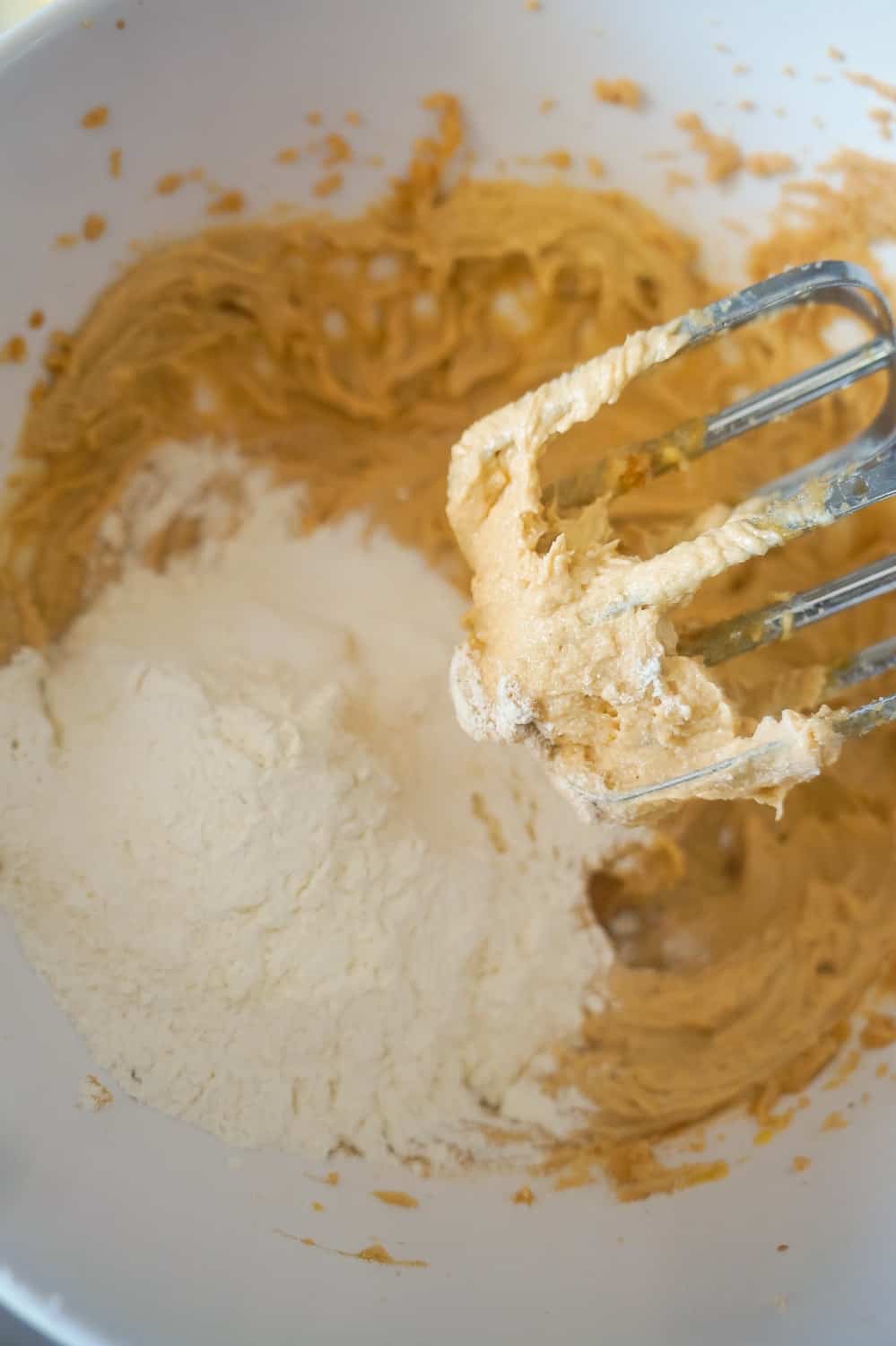 flour being added to peanut butter cookie dough in mixing bowl