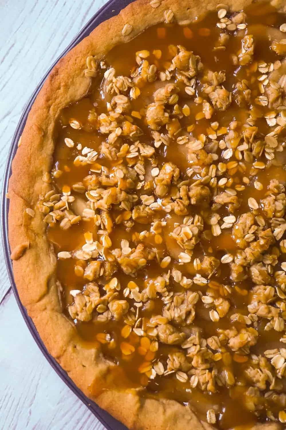 Peanut Butter Apple Pie Cookie Pizza is an easy dessert recipe for peanut butter lovers. A peanut butter cookie crust is topped with apple pie filling, peanut butter oat crumble and drizzled with caramel syrup.