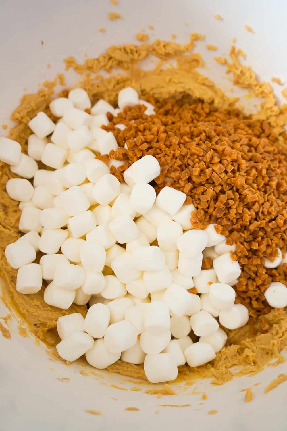 mini marshmallows and Skor bits in a mixing bowl with peanut butter cookie dough