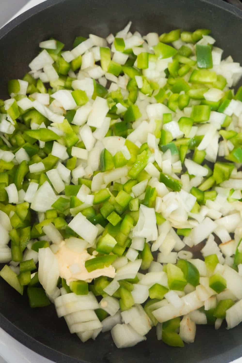 diced onions and diced green peppers in a frying pan