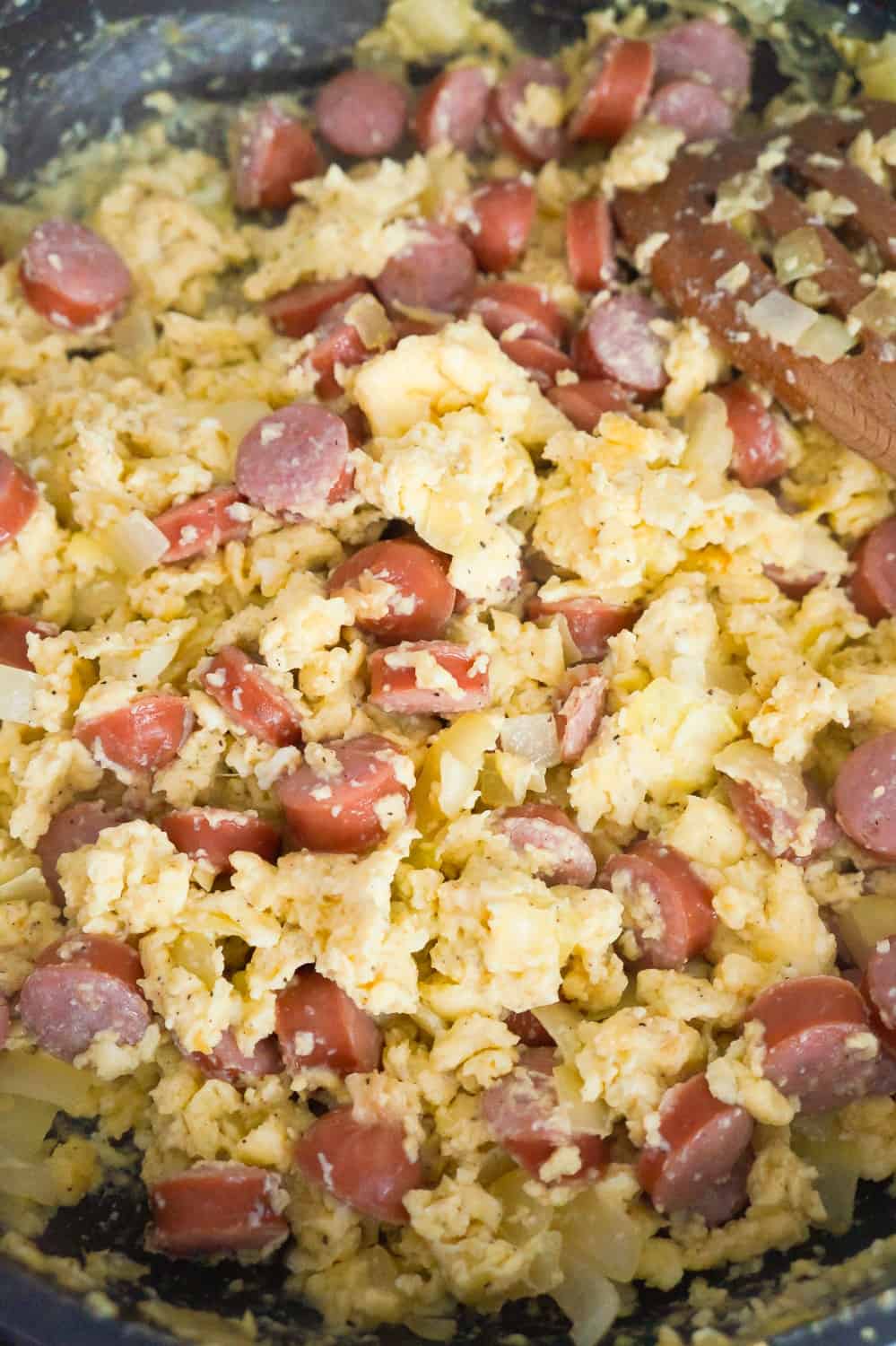 cooked eggs and sausage pieces in a frying pan